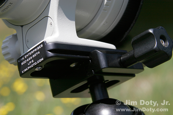 Telephoto lens mounting plate in the jaws of a tripod head. Photo copyright Jim Doty Jr.